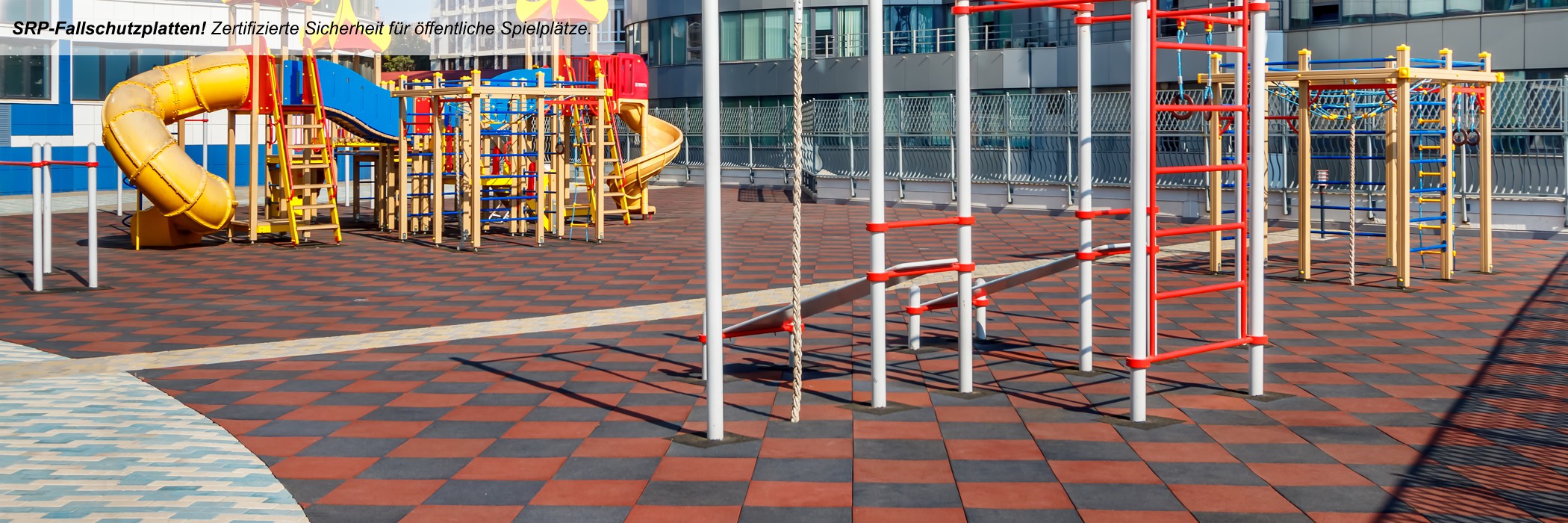 Kinderspielplatz mit roten Fallschutzplatten, Kinderspielgeräte mit schwarzen und gelben Wänden